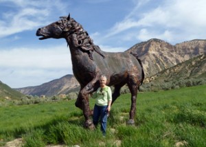 Lady posing by metal horse.
